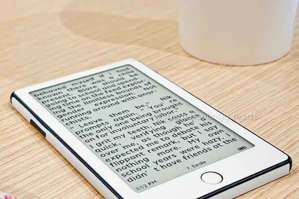Xteink X4 Pro posée à plat sur une table de café en bois clair, une page de roman affichée sur son écran e-ink