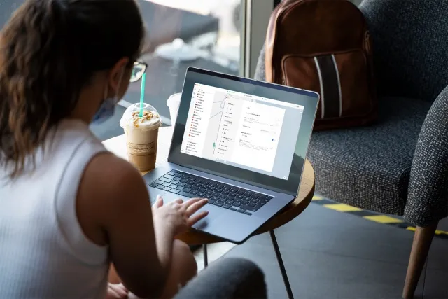 Digital nomade au travail sur le wifi d'un café, sac à dos posé à côté