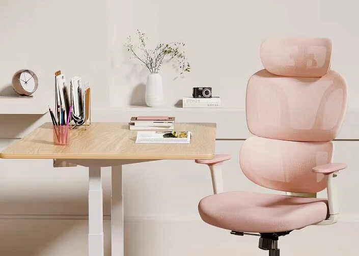 Chaise Flexispot BS5 rose à côté d'un bureau assis-debout en bois clair, dans un coin bureau cosy