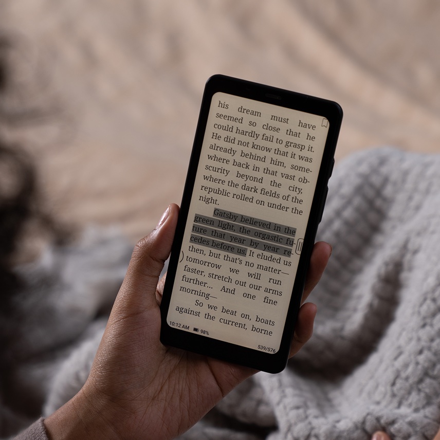 Page de roman affichée en noir et blanc sur l'écran e-ink de la Boox Palma 2, tenue en main avec un éclairage frontal chaud
