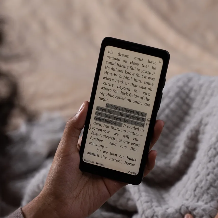 Page de roman affichée en noir et blanc sur l'écran e-ink de la Boox Palma 2, tenue en main avec un éclairage frontal chaud