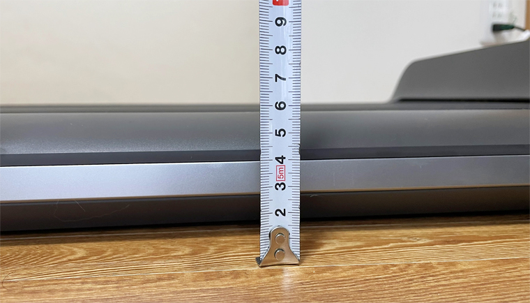 Mètre ruban mesurant l'épaisseur de 13 cm du WalkingPad P1 posé au sol