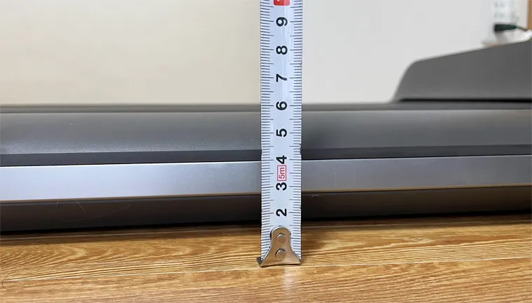 Mètre ruban mesurant l'épaisseur de 13 cm du WalkingPad P1 posé au sol