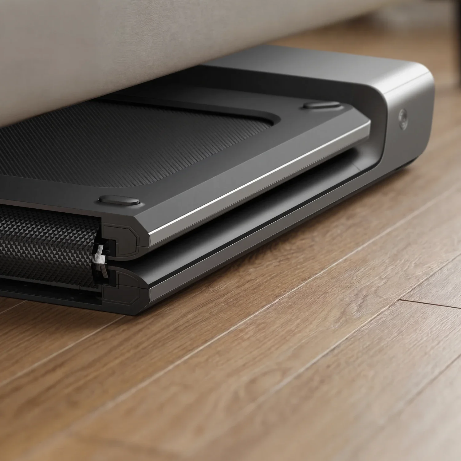WalkingPad P1 plié et rangé à plat sous un canapé, châssis aluminium visible