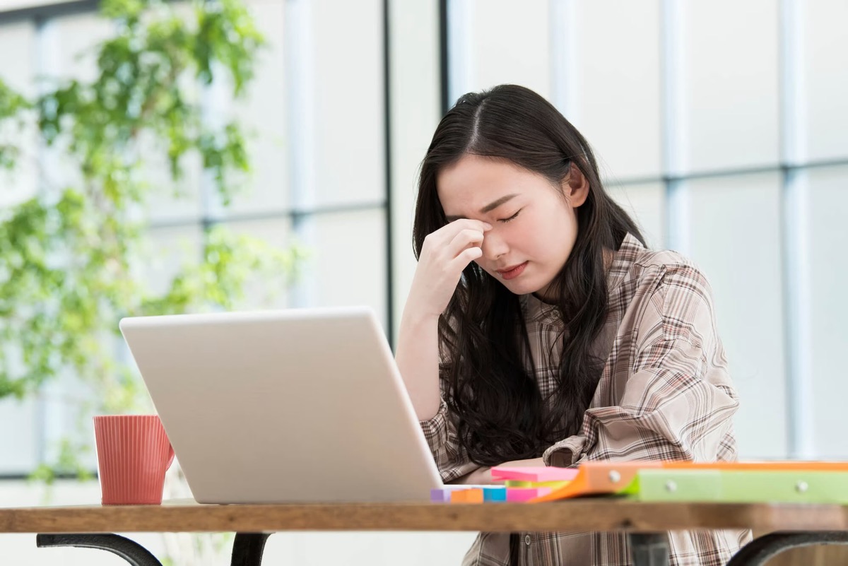 Jeune femme se massant les yeux, fatiguée devant son écran portable