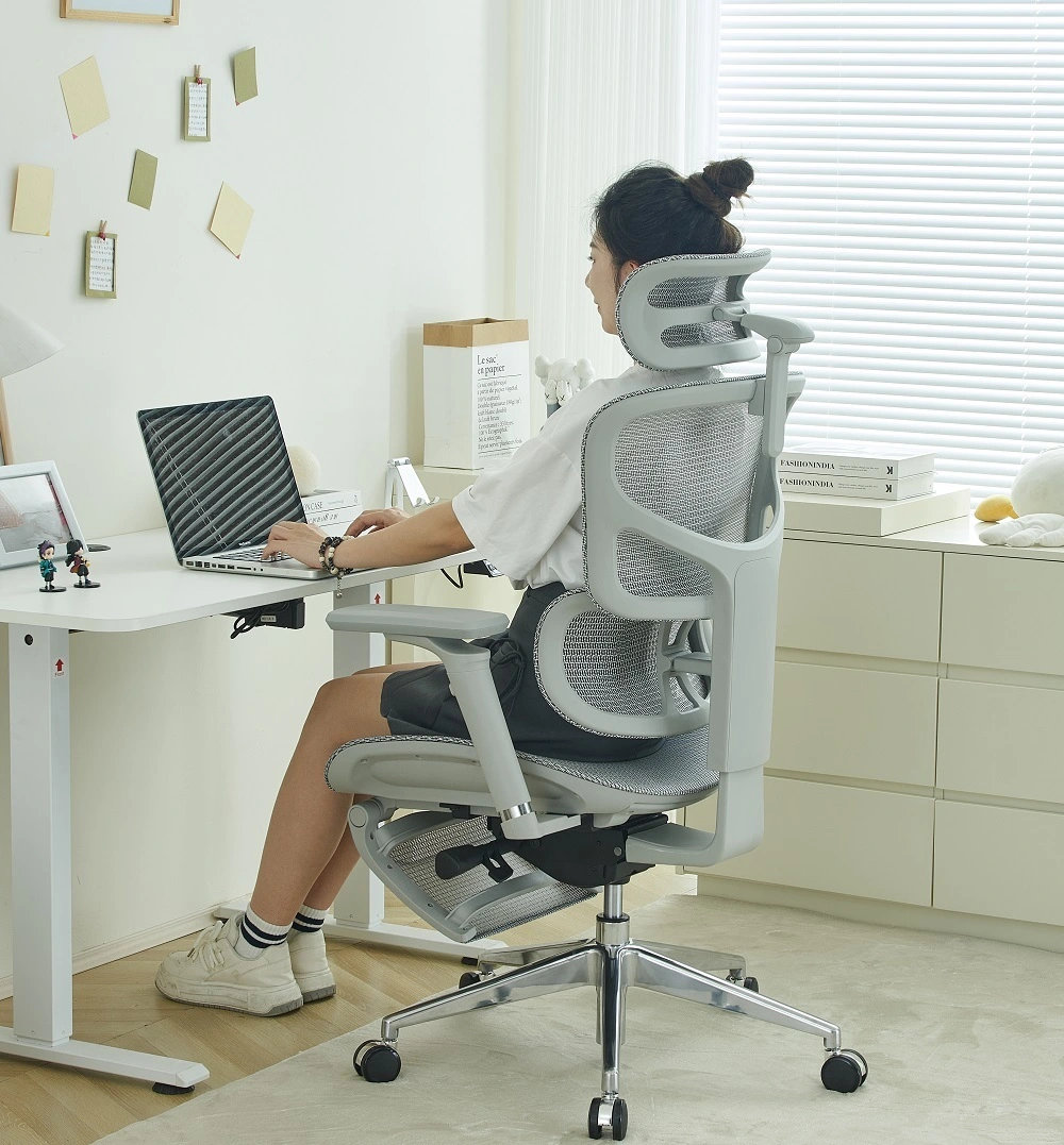 Femme travaillant sur un ordinateur portable dans une chaise ergonomique en mesh à appui-tête