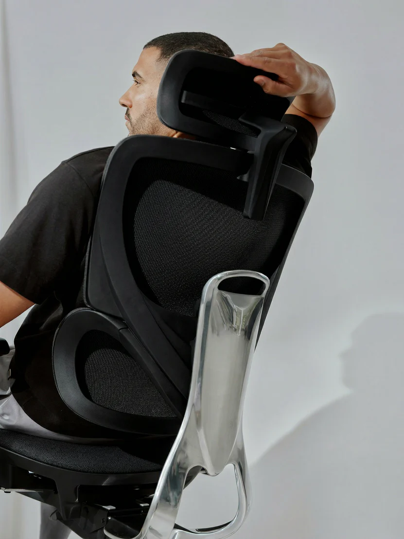Personne assise ajustant l'appui-tête de la chaise full-mesh CLOUVOU MasterSeat