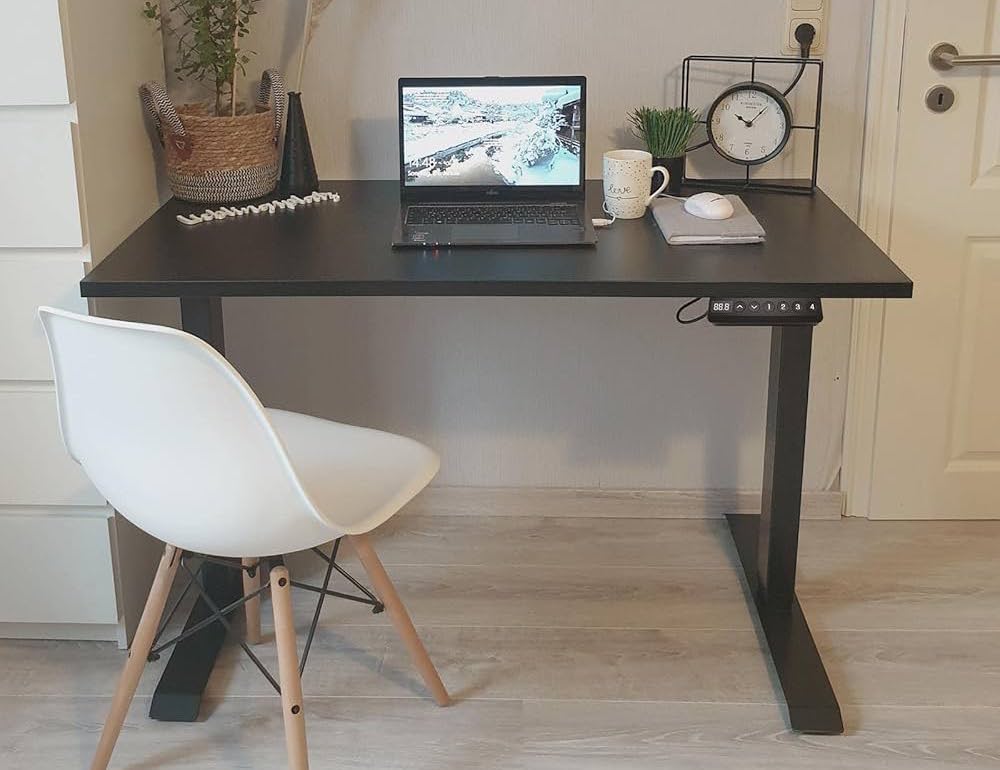 Bureau assis-debout FlexiSpot E5 noir avec ordinateur portable et chaise blanche dans un coin cozy