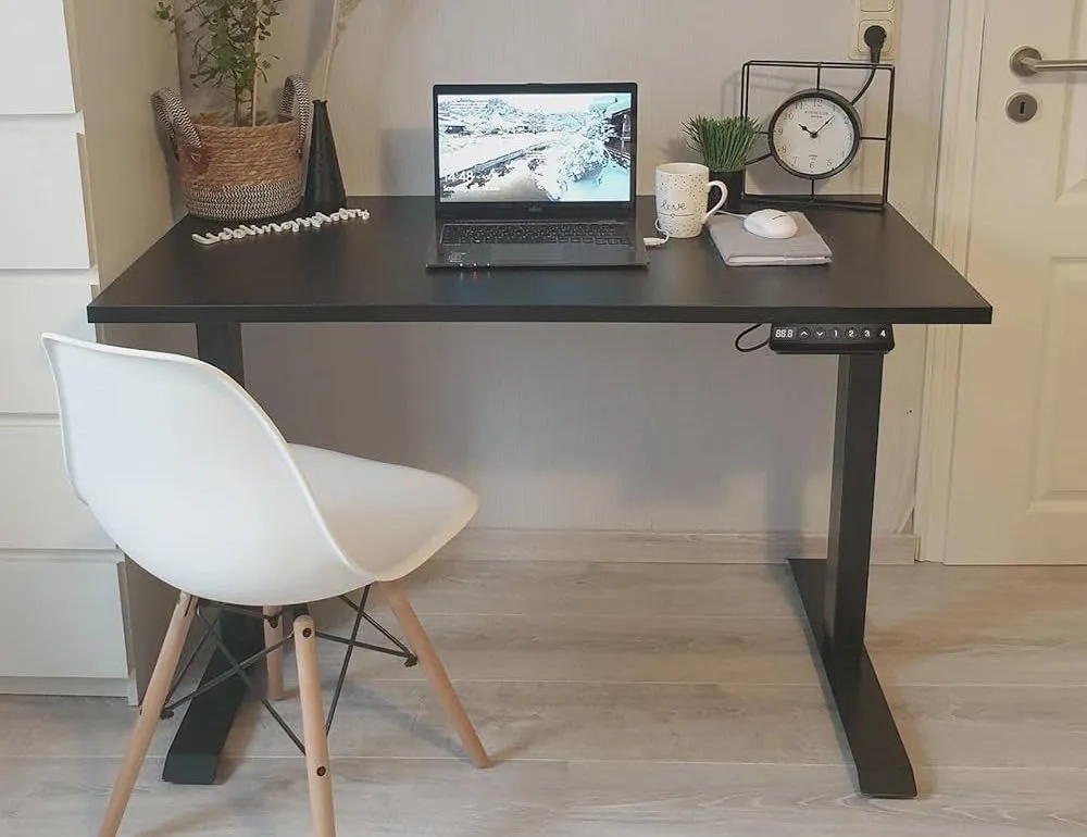 Bureau assis-debout FlexiSpot E5 noir avec ordinateur portable et chaise blanche dans un coin cozy