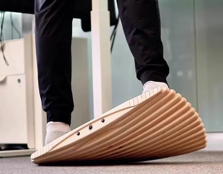 Pied posé sur une balance board en bois lamellé devant un bureau