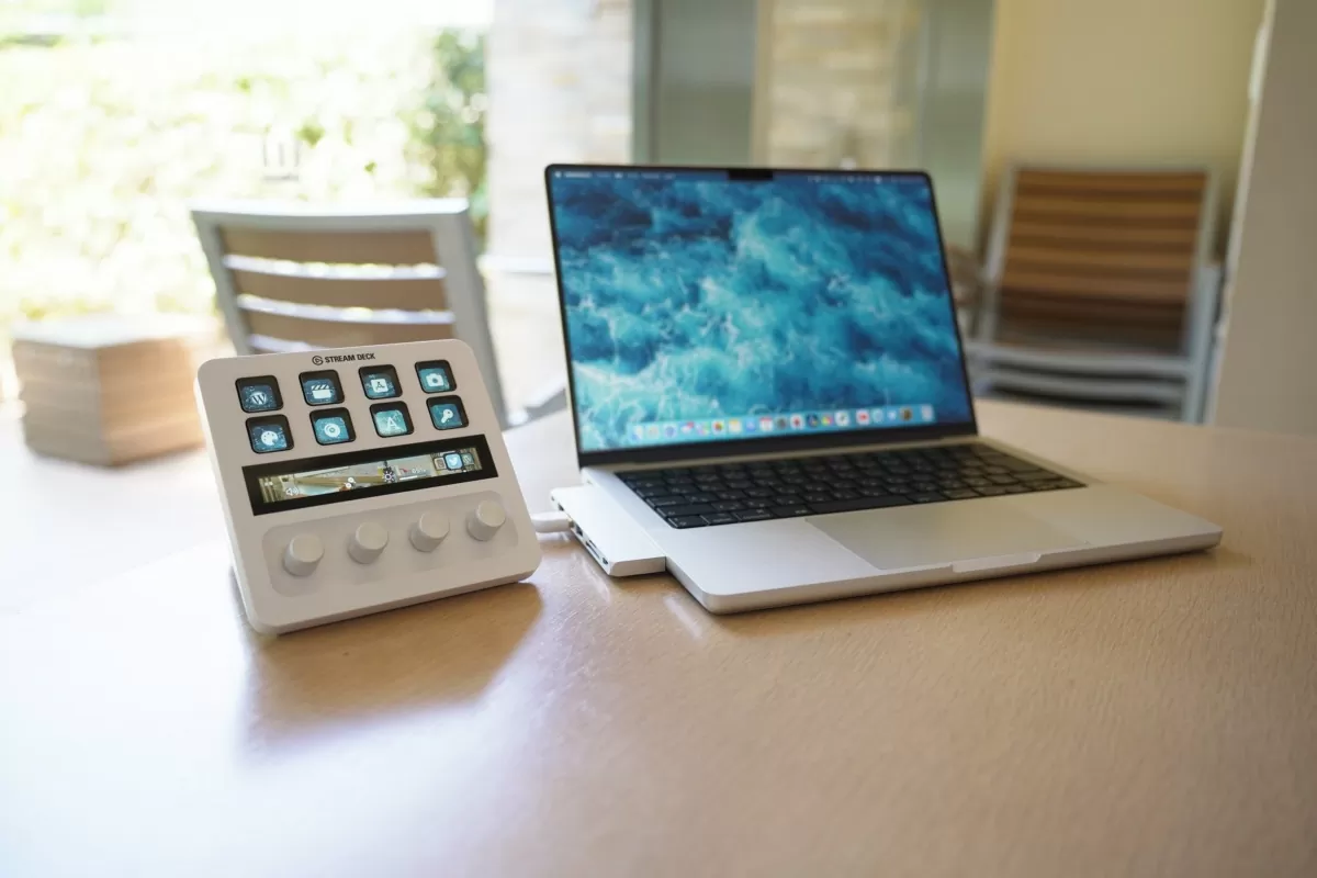 Stream Deck Plus posé à côté d'un MacBook sur un bureau clair