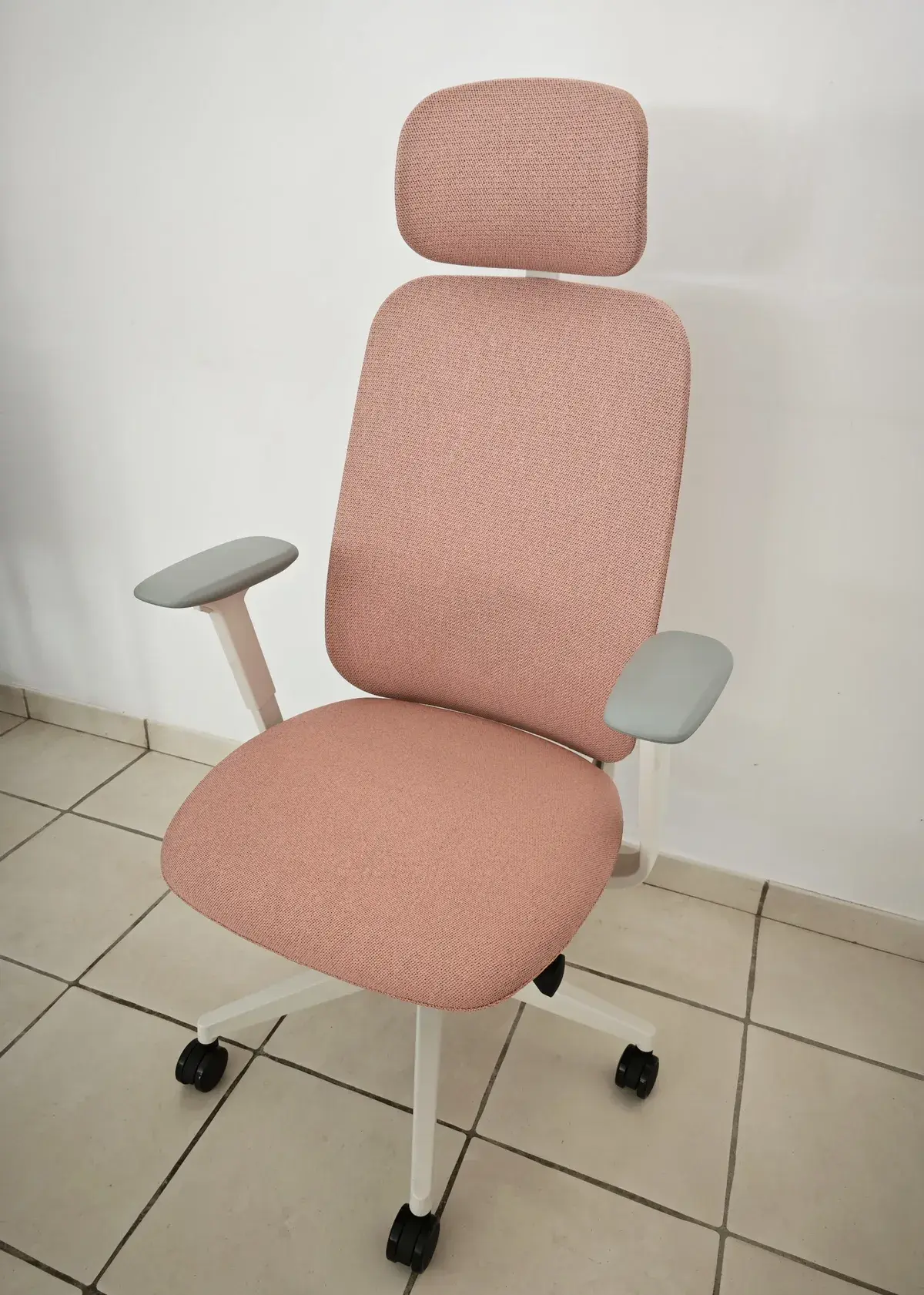 Chaise ofinto Premium Cloud en tissu rose avec accoudoirs gris et appui-tête, posée sur un carrelage beige